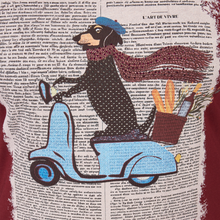 Load image into Gallery viewer, A vintage-style art print featuring a black-and-white dog wearing a blue hat and blue boots, holding a yellow-orange basket, set over a background of printed book pages.

