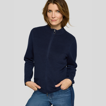 Load image into Gallery viewer, A woman wearing a navy blue ribbed zip-up jacket with a mock neck, paired with blue jeans, photographed against a solid light gray background.
