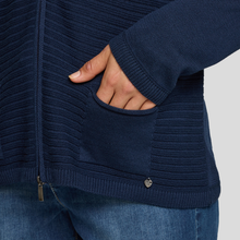 Load image into Gallery viewer, Navy blue sweater with a hand in the pocket on a light gray background
