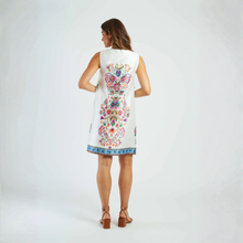 Load image into Gallery viewer, Woman wearing a white dress with colorful floral embroidery on a plain background
