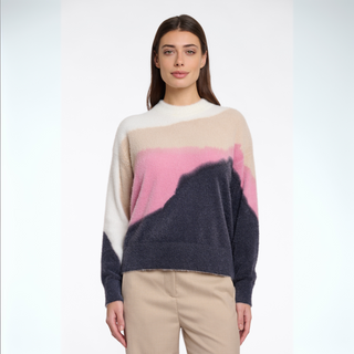 Woman wearing a color-blocked sweater with beige, pink, and navy design on a white background
