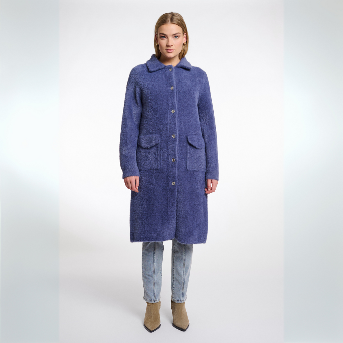 Woman wearing a long blue coat on a white background