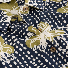Load image into Gallery viewer, Close-up of a patterned shirt with floral and polka dot designs on a navy background.

