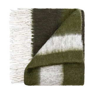 A Scatterbox throw folded with tones of green, black and cream and thick white fringe along the side