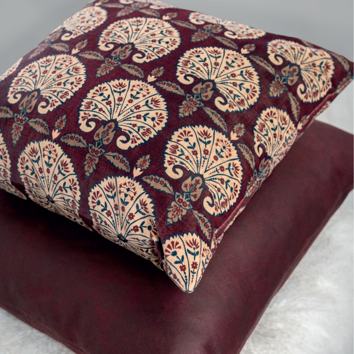 A promo shot of the Persia Aubergine cushion on top of another aubergine cushion