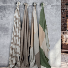 Load image into Gallery viewer, Four Scatterbox throws hanging on a grey wall with different shades of cream, brown, beige and green

