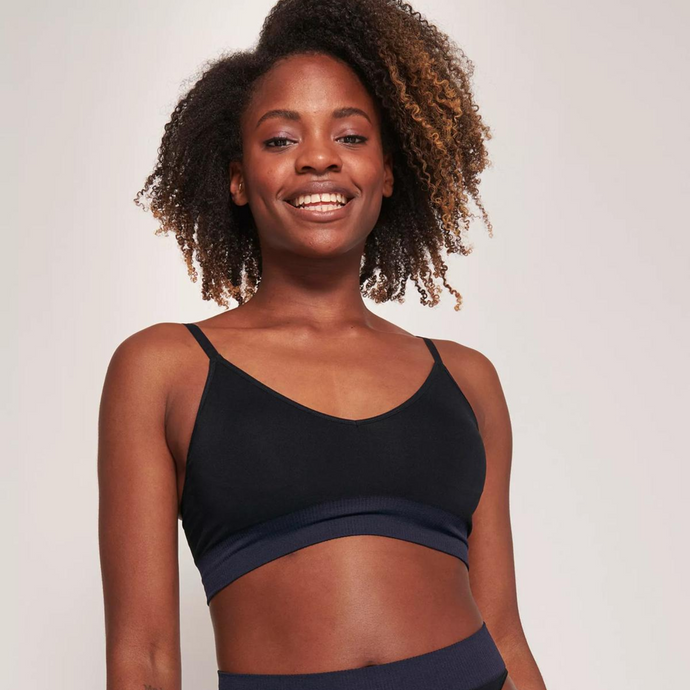 A close up picture of a model smiling while wearing the Sloggi Ever Infused Aloe Bralette. 