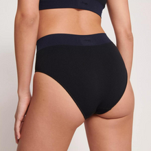 Load image into Gallery viewer, A model showing the back of the Sloggi Ever Infused Aloe High Waist Brief In Black standing with their left leg forward. 
