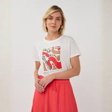 Load image into Gallery viewer, Woman wearing a white t-shirt with a graphic design and a red skirt on a plain background
