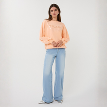 Load image into Gallery viewer, Woman wearing a peach sweatshirt with 'CHICAGO' text and light blue jeans on a white background
