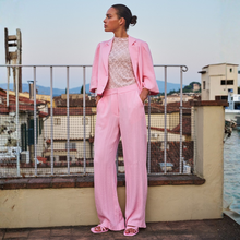 Load image into Gallery viewer, Woman in a pink suit standing on a rooftop with a scenic background
