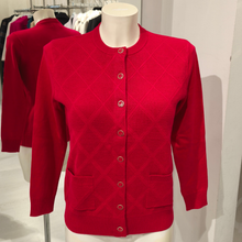 Load image into Gallery viewer, The Castle Poppy Cardigan displayed on a mannequin, showcasing its vibrant colour, classic diamond pattern and timeless style, perfect for effortless layering
