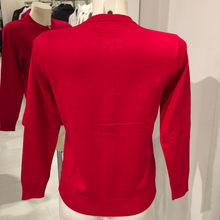 Load image into Gallery viewer, The Castle Poppy Cardigan presented on a mannequin, highlighting its eye-catching red shade, traditional diamond knit design and versatile appeal.
