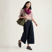 Load image into Gallery viewer, A woman models a striped long-sleeve top, dark wide-leg cropped pants, a purple scarf, and an olive green tote bag against a plain off-white studio background.
