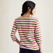 Load image into Gallery viewer, A woman shown from the back wearing a three-quarter sleeve striped top with horizontal bands of pink, olive green, and cream on a light beige background.
