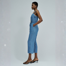 Load image into Gallery viewer, Woman wearing a blue denim jumpsuit on a light gray background
