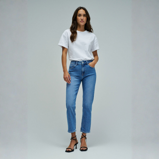 Woman wearing a white t-shirt and blue jeans on a gray background