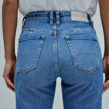 Load image into Gallery viewer, Blue jeans being worn with a visible brand label on a plain background

