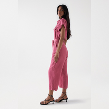 Load image into Gallery viewer, Model with long dark hair standing sideways wearing Salsa cropped leg jumpsuit in old pink color. 
