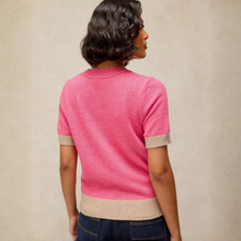 Load image into Gallery viewer, A woman shown from the back wearing a short-sleeve knit top in bright pink with beige ribbed trim at the sleeve cuffs and hem, paired with dark blue jeans against a neutral beige studio background.
