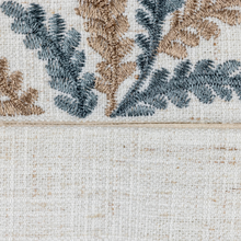 Load image into Gallery viewer, Close-up of a textured fabric with floral patterns in brown and blue on a beige background
