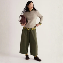 Load image into Gallery viewer, A woman modeling a light beige knit sweater with a green and yellow floral collar and cuffs, paired with wide-leg olive green pants and dark brown shoes, holding a dark brown bag against a plain off-white background.

