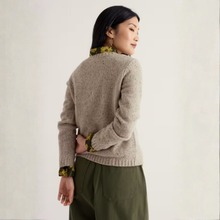 Load image into Gallery viewer, A woman shown from the back wearing a beige knit sweater with contrasting green and yellow patterned collar and cuff trim, paired with olive green pants, against a plain off-white studio background.
