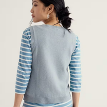 Load image into Gallery viewer, A woman shown from the back wearing a light blue knit sweater vest over a light blue and white striped long-sleeve top, against a plain off-white studio background.

