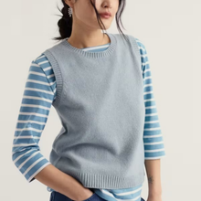 Load image into Gallery viewer, A woman wearing a light blue ribbed knit sweater vest over a light blue and white striped long-sleeve shirt, shown from the chest down against a plain light background.
