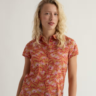 Woman wearing a short-sleeve, patterned dress with a neutral background