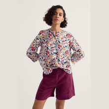 Load image into Gallery viewer, Woman wearing a floral blouse and purple shorts on a plain background
