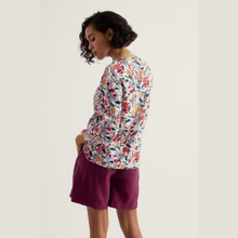 Load image into Gallery viewer, Woman wearing a floral top and purple shorts on a plain background
