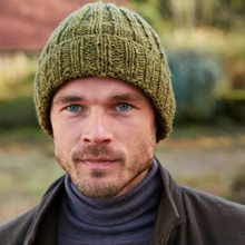 Load image into Gallery viewer, A close-up portrait of a man wearing a textured olive green knit beanie and a dark gray turtleneck, set against a softly blurred outdoor background.
