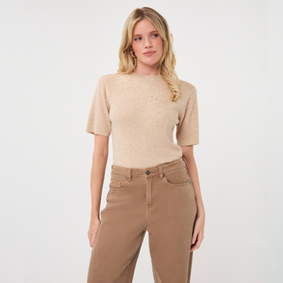 A woman modeling a beige short-sleeve knit top with subtle dotted texture, paired with brown high-waisted jeans, against a plain white studio background.