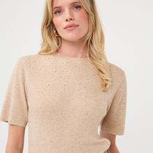 Load image into Gallery viewer, A woman wearing a beige short-sleeve knit top with tiny speckled details, photographed against a clean white background.
