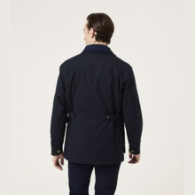 Load image into Gallery viewer, A man viewed from the back wearing a dark navy blue jacket with a belted waist and dark trousers, set against a plain off-white studio background.
