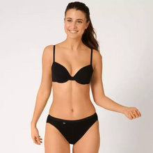 Load image into Gallery viewer, A model wearing the Sloggi Tai Brief in Black looking to the left and smiling with her right arm raised.
