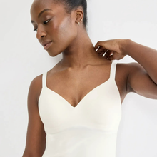 Load image into Gallery viewer, A woman wearing a white V-neck camisole top, shown from the chest up against a plain light background.
