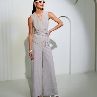 Woman wearing a gray sleeveless jumpsuit against a white background