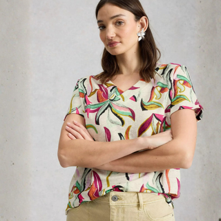 Coloured print top on women with light trousers and grey background 