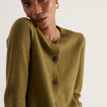 Load image into Gallery viewer, A close-up of a model wearing a textured olive green knit cardigan with dark brown buttons, set against a plain off-white background.
