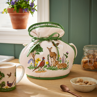 Teapot with nature-themed design on a kitchen counter with a mug and other items.