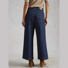 Load image into Gallery viewer, Back view of Model posing, Wearing White Stuff Tia Dark Denim in dark denim, with a light grey background.
