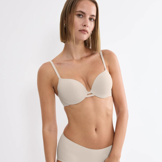 Woman wearing a beige bra and underwear set on a white background