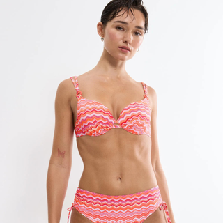 Woman wearing a pink and orange zigzag patterned bikini on a white background