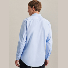 Load image into Gallery viewer, A man wearing a light blue long-sleeve button-down shirt, shown from the back against a plain beige studio background.
