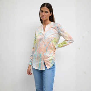 Woman wearing a patterned blouse and blue jeans against a white background
