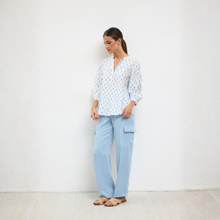 Woman wearing a light blue patterned shirt and matching pants against a white background