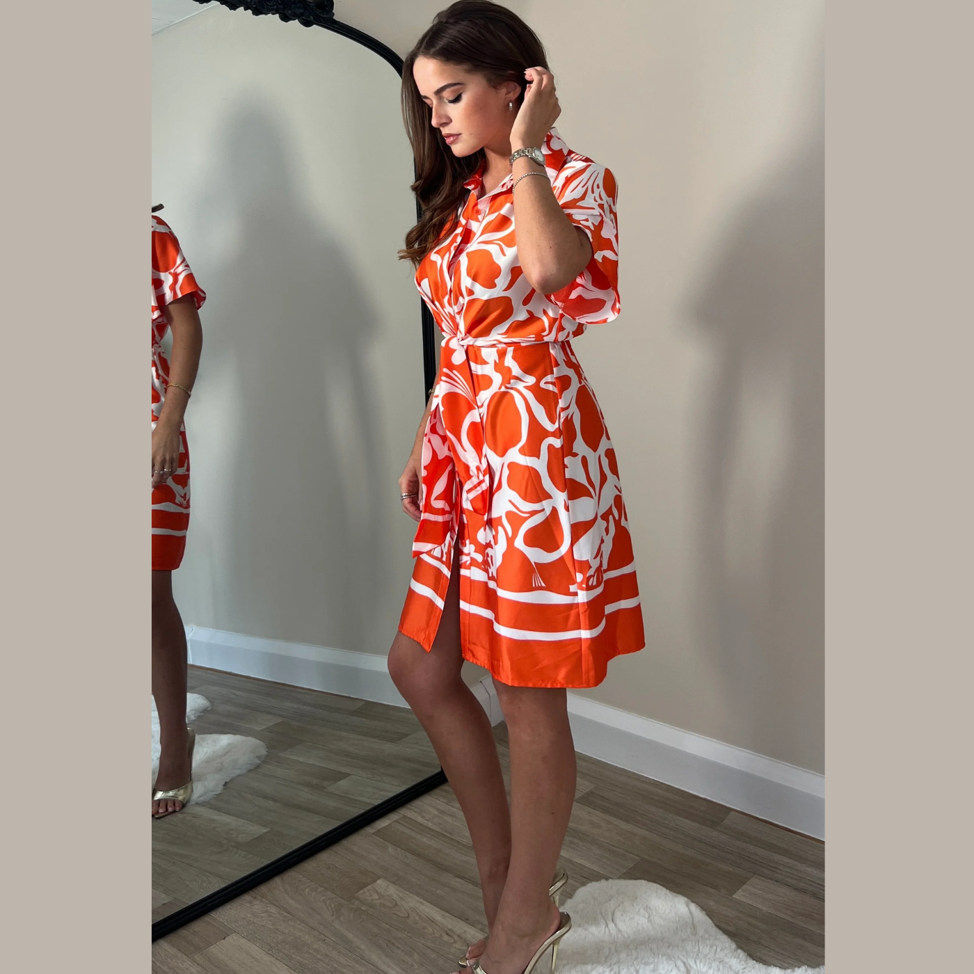 female model wearing girl in mind verity shirt dress in orange colour with hand on hair 