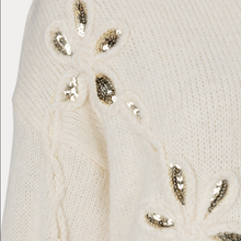 Load image into Gallery viewer, Close-up of a cream-colored knit sweater featuring textured cable-knit patterns and decorative sequined floral motifs in metallic gold and silver.
